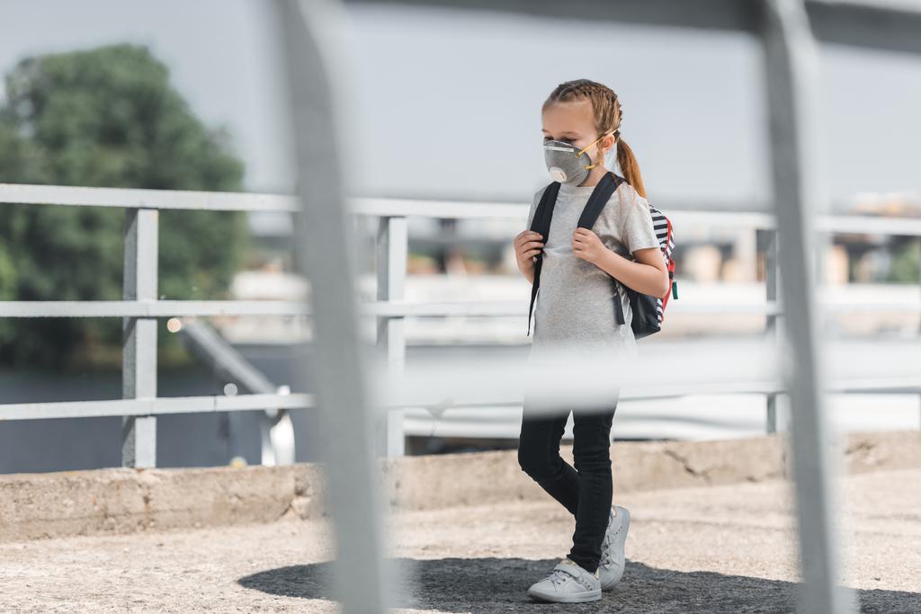 Kind in Schutzmaske läuft mit Schultasche auf Brücke, Luftverschmutzungskonzept - Foto, Bild