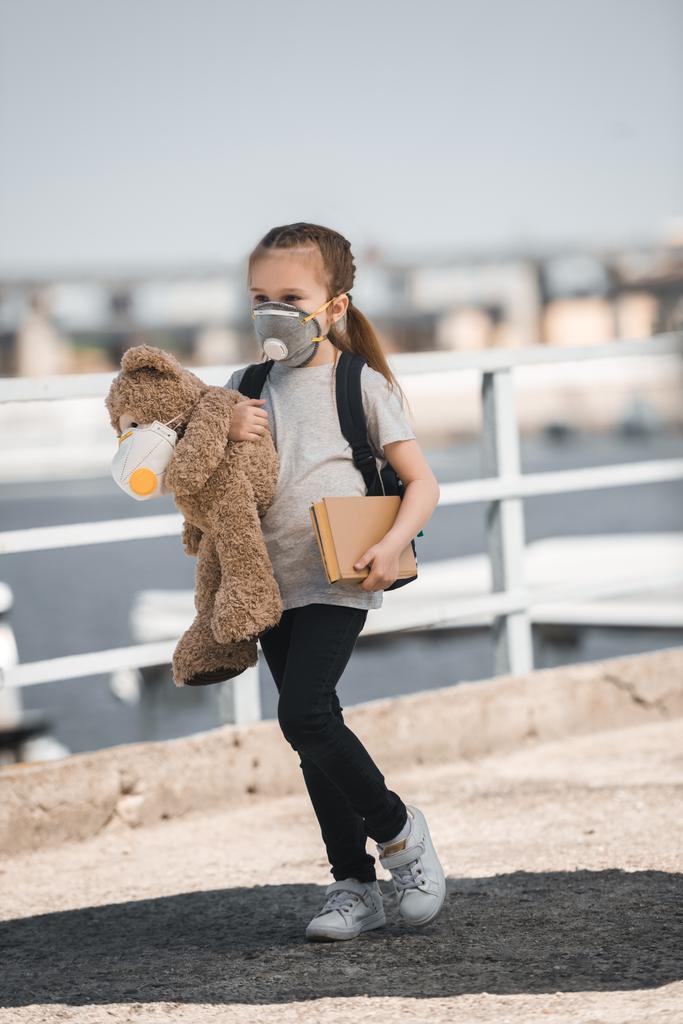 enfant en masque de protection tenant ours en peluche et livre sur le pont, concept de pollution atmosphérique
 - Photo, image