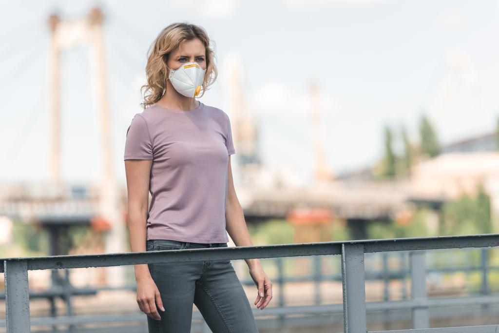 Kobieta w maska ochronna, stojąc na moście i odwracając, pojęcie zanieczyszczenia powietrza - Zdjęcie, obraz