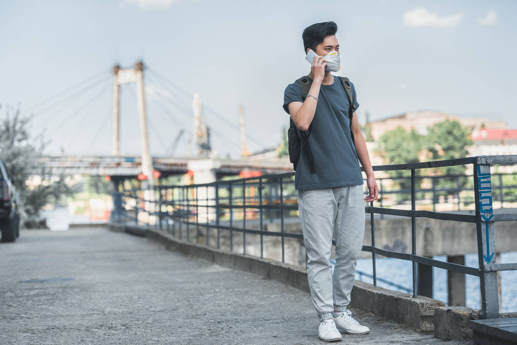 asiático adolescente em máscara protetora falando por smartphone na ponte, conceito de poluição do ar
 - Foto, Imagem