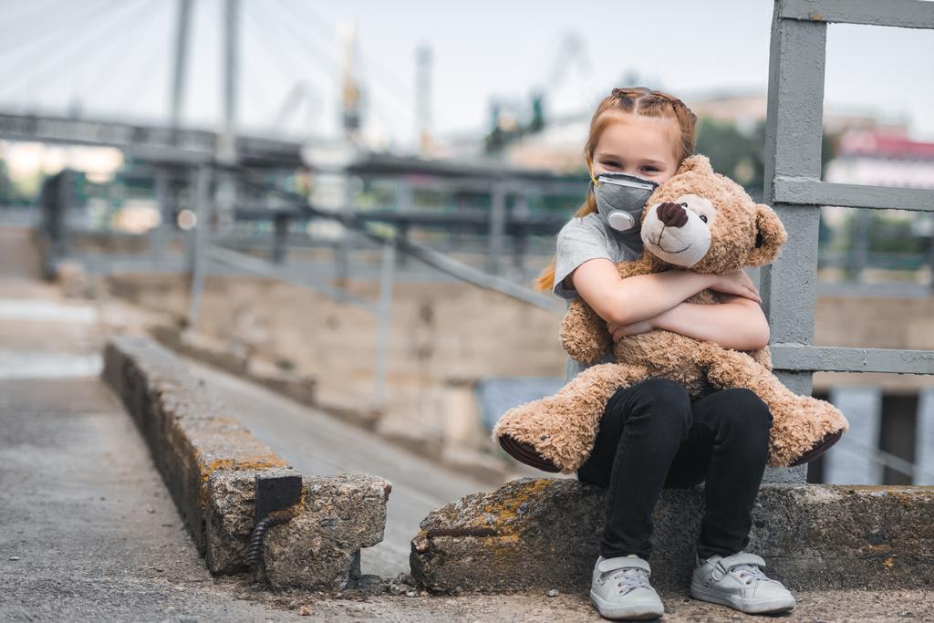 dziecko w maska ochronna przytulanie pluszowego misia na ulicy, pojęcie zanieczyszczenia powietrza - Zdjęcie, obraz