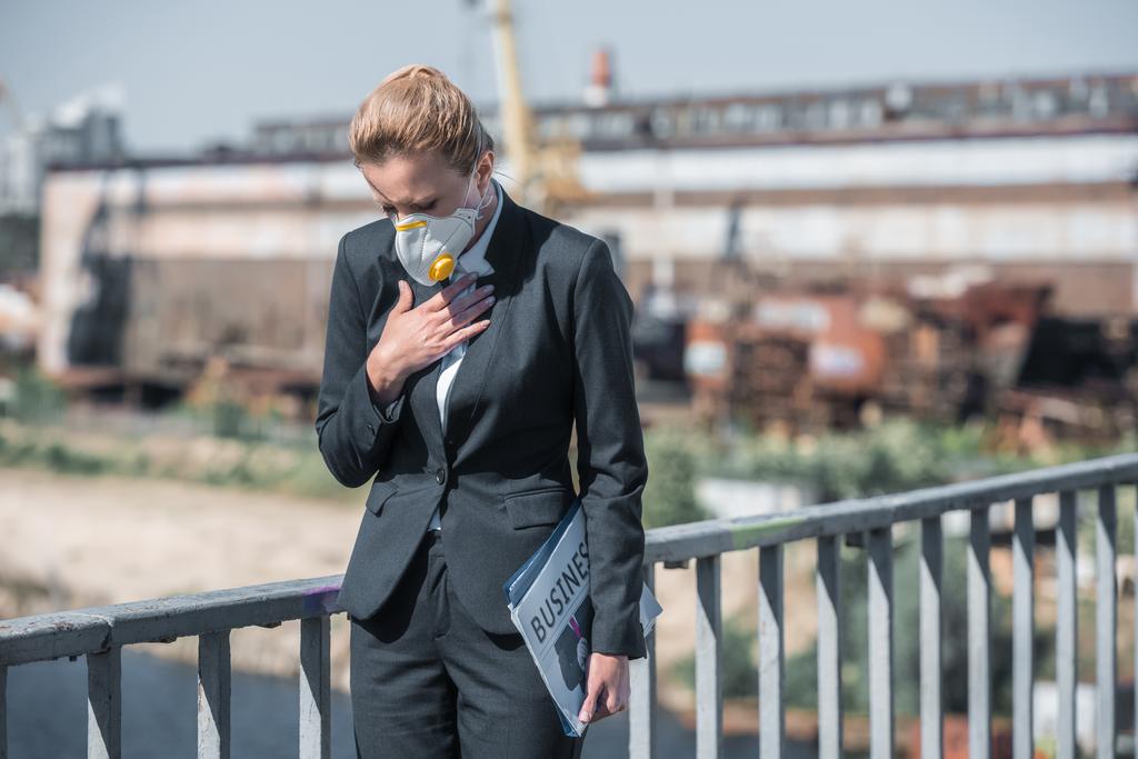 бізнес-леді в захисній масці торкаючись грудей на мосту, концепція забруднення повітря
 - Фото, зображення
