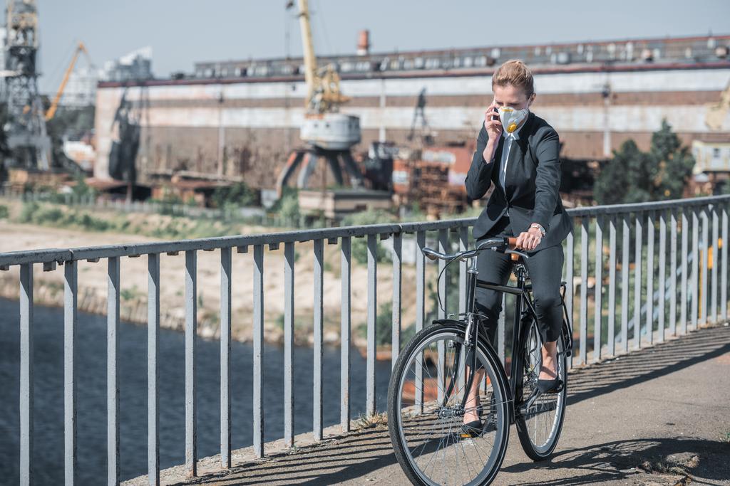 mujer de negocios en máscara protectora montar en bicicleta en el puente y hablar por teléfono inteligente, concepto de contaminación del aire
 - Foto, imagen
