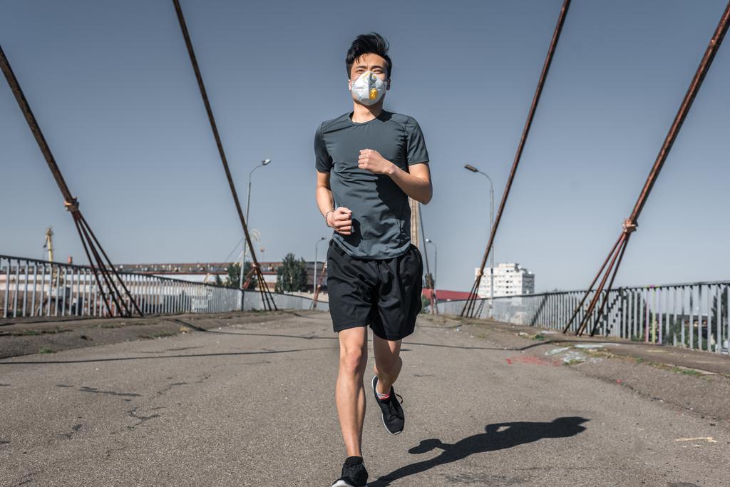 Ασιατικές έφηβος εκτέλεση σε προστατευτική μάσκα σε γέφυρα, η έννοια της ρύπανσης του αέρα - Φωτογραφία, εικόνα