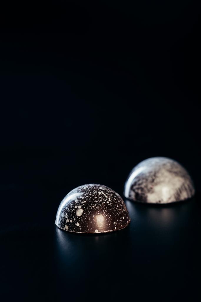close up vista de dois doces de chocolate no fundo preto
  - Foto, Imagem