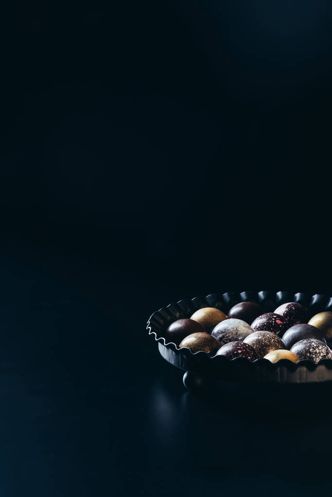 pile de divers bonbons au chocolat dans un bol sur fond noir
 - Photo, image