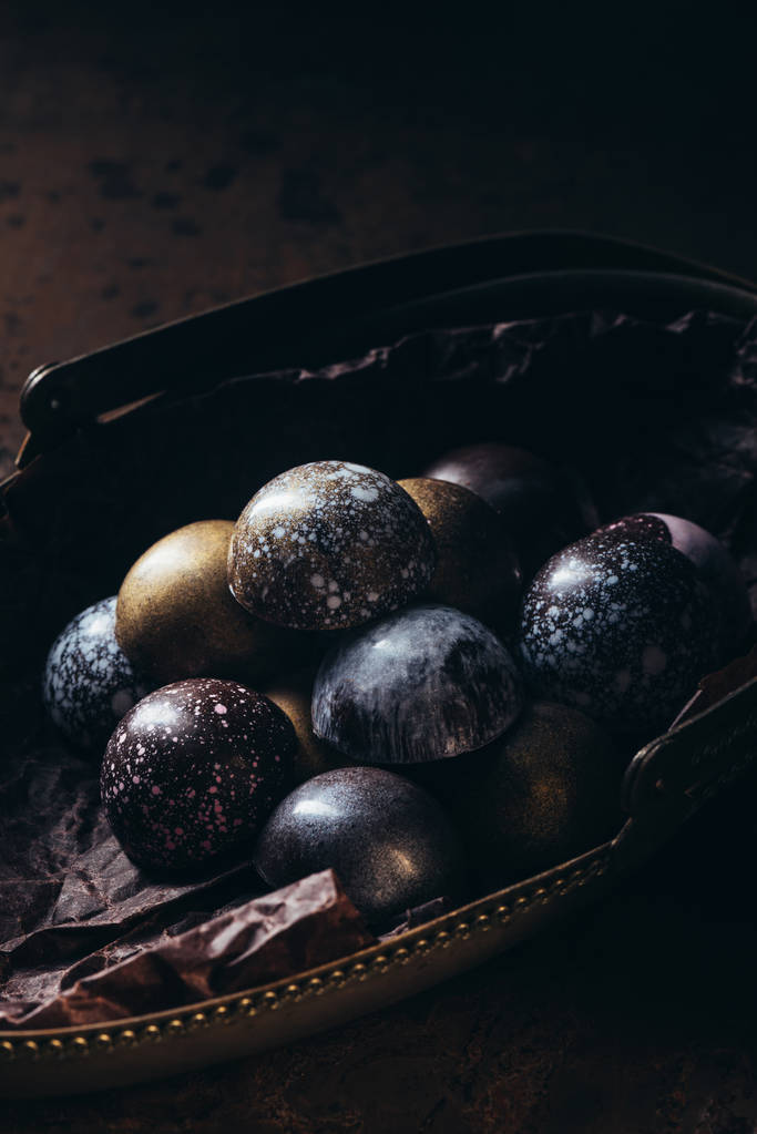 vista de cerca de la pila de diferentes caramelos de chocolate en la cesta de metal en la mesa de madera
 - Foto, imagen