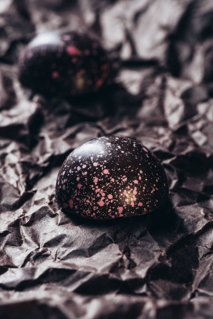 Προβολή closeup των δύο καραμέλες από σοκολάτα με ροζ πιτσιλιές του τσαλακωμένο χαρτί - Φωτογραφία, εικόνα
