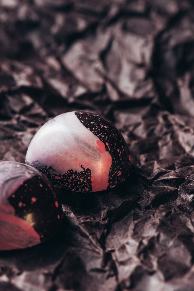 tiro de perto de dois doces de chocolate com salpicos rosa em papel amassado
 - Foto, Imagem