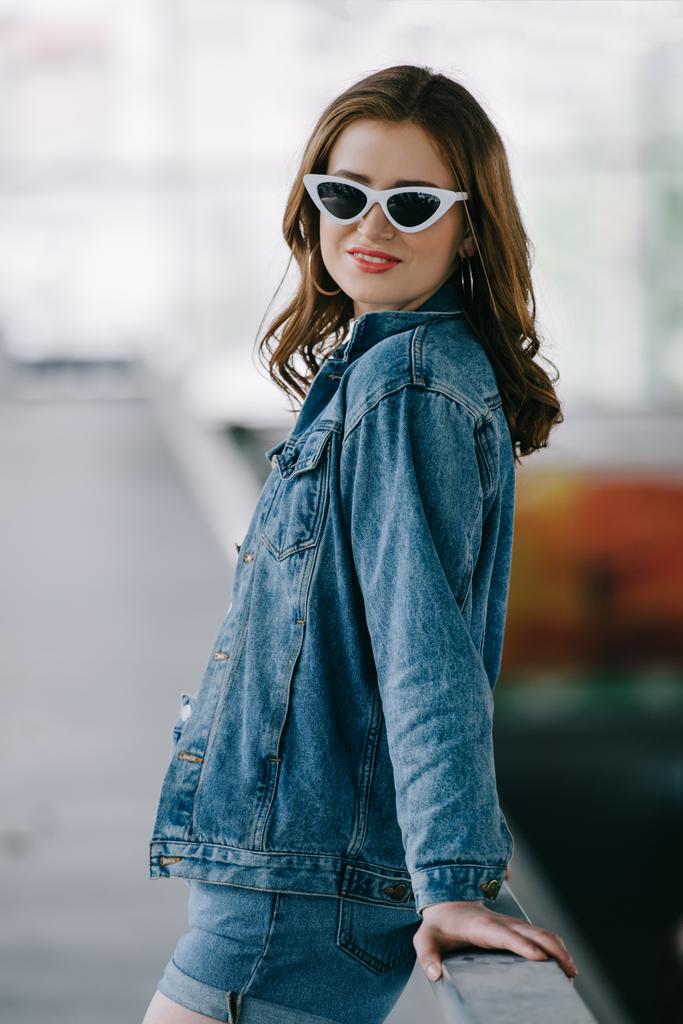 вид збоку усміхненої жінки в ретро сонцезахисних окулярах і модний джинсовий одяг
 - Фото, зображення