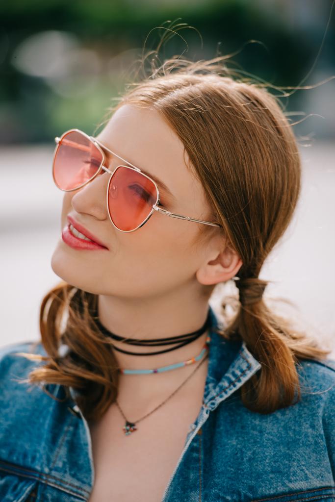 retrato de hermosa chica sonriente en gafas de sol y chaqueta de mezclilla mirando al aire libre
 - Foto, imagen