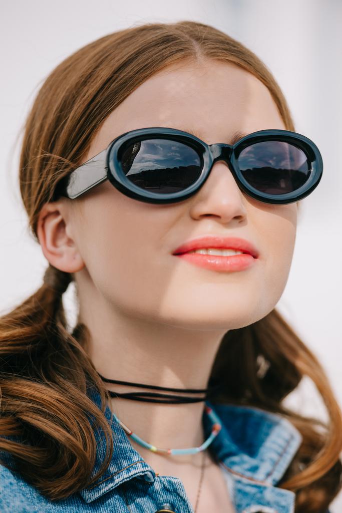 retrato de cerca de la hermosa mujer joven en gafas de sol mirando al aire libre
 - Foto, imagen