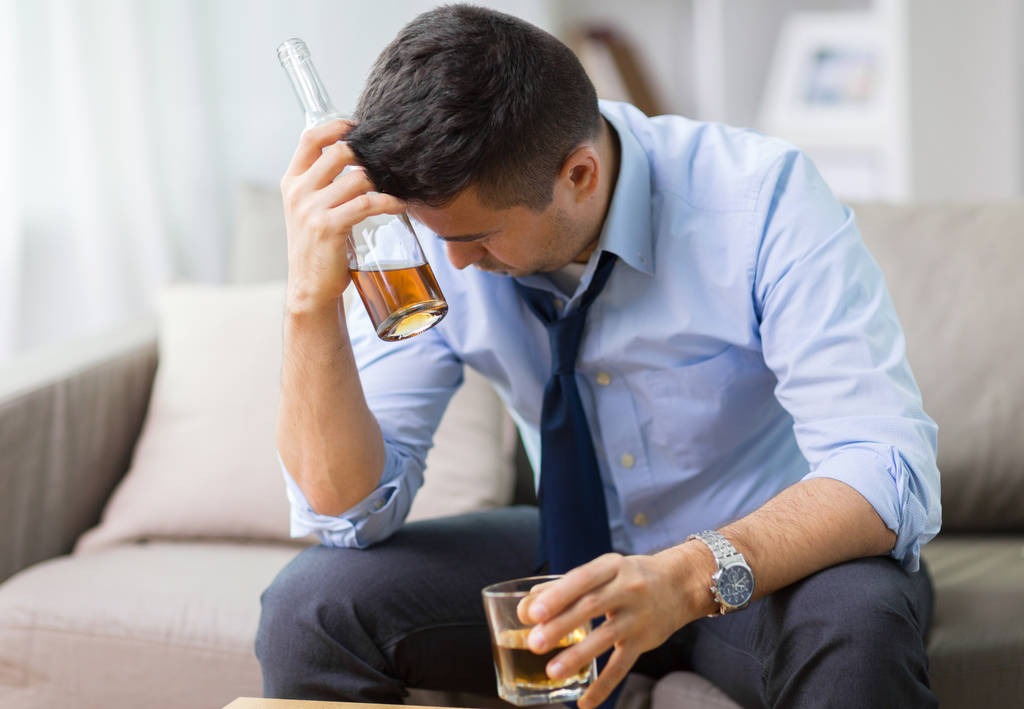Alkoholiker mit Flasche trinkt Whisky zu Hause - Foto, Bild