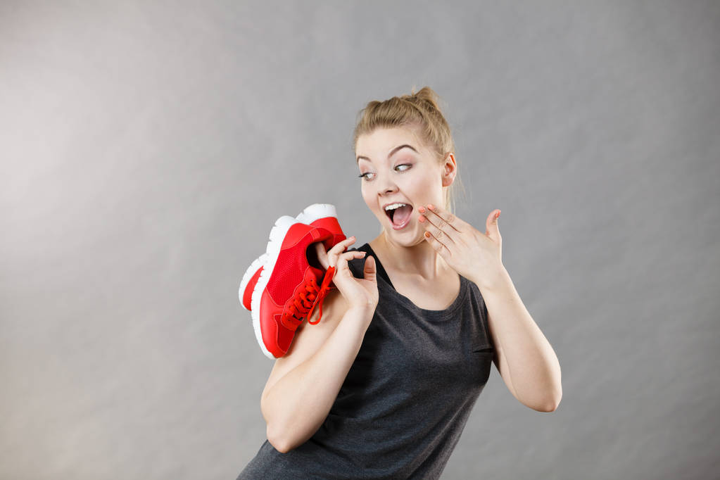Feliz desportivo sorrindo mulher apresentando sportswear treinadores sapatos vermelhos, calçado confortável perfeito para treino e treinamento
. - Foto, Imagem