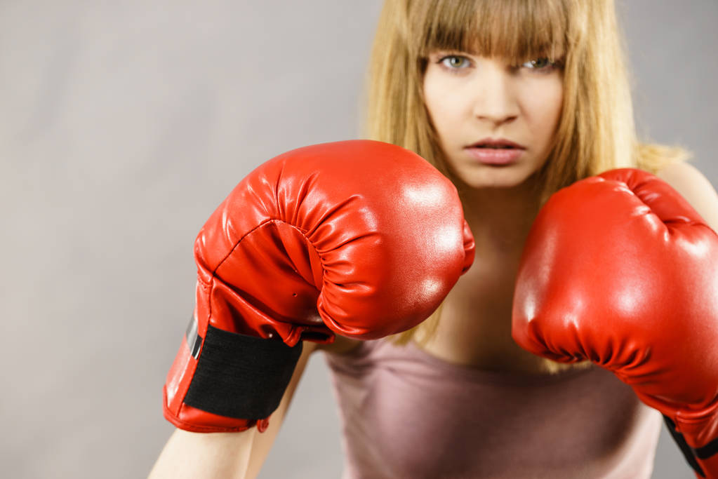 Mujer deportiva con guantes de boxeo rojos, peleando. Estudio grabado en gris, fondo. - Foto, Imagen