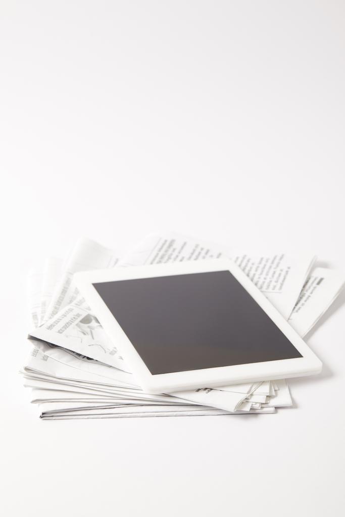 digitaalinen tabletti tyhjällä näytöllä kasa sanomalehtiä, valkoinen
 - Valokuva, kuva