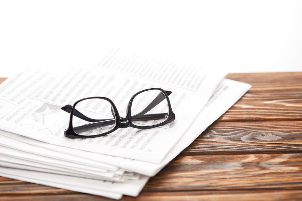 lunettes sur pile de journaux sur table en bois, sur blanc
 - Photo, image