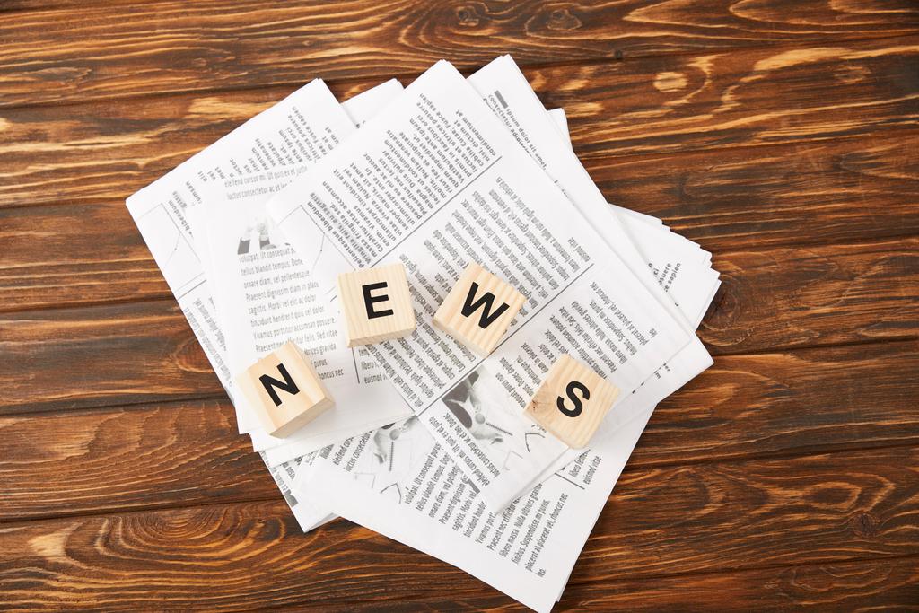 ylhäältä näkymä sana uutiset aakkosista kuutiot kasaan sanomalehtiä puinen tausta
 - Valokuva, kuva