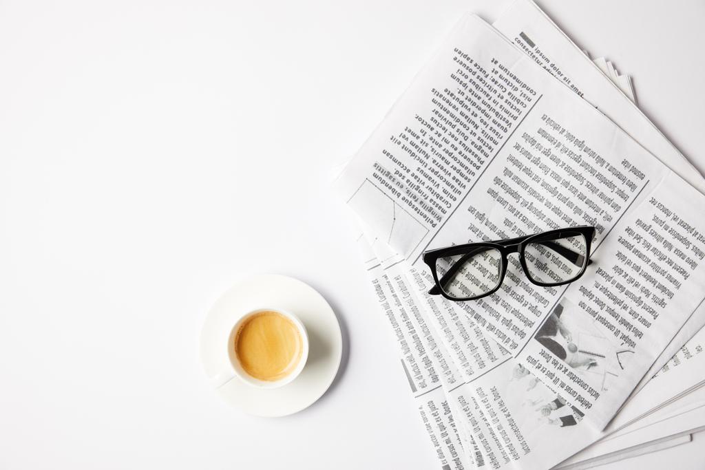 Widok góry filiżankę kawy i okulary na gazety, na biały stół - Zdjęcie, obraz