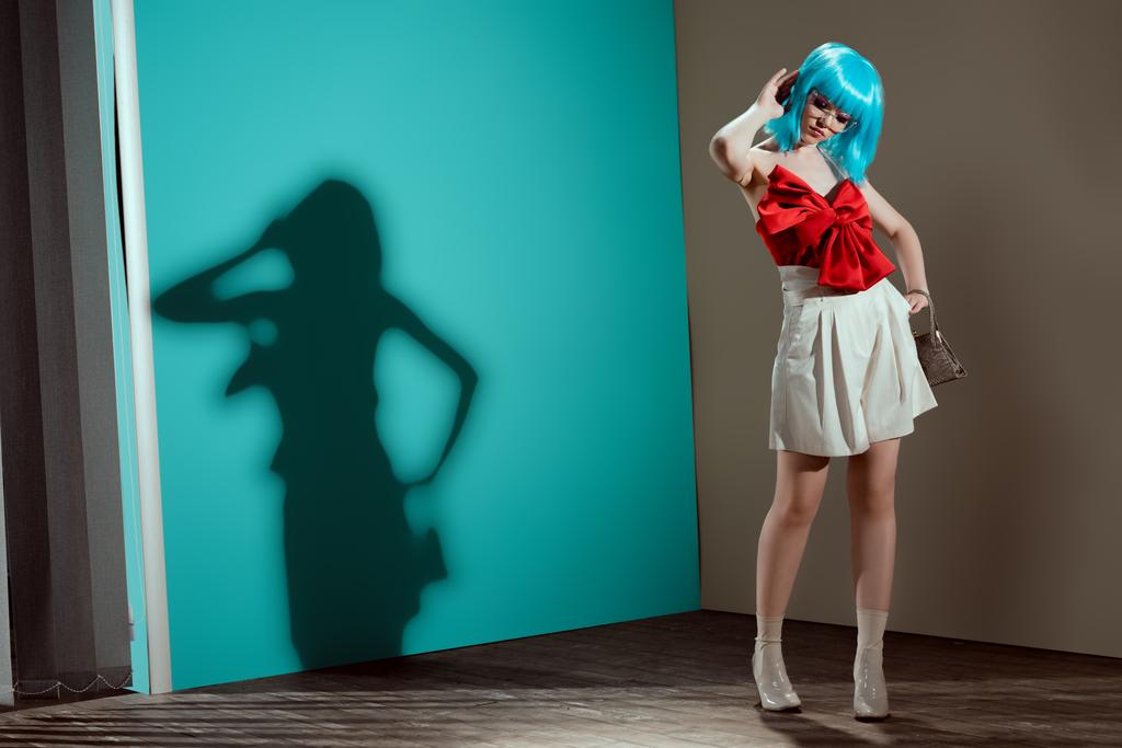 vista completa de la hermosa modelo femenino de moda en la peluca azul posando y mirando hacia abajo
 - Foto, imagen