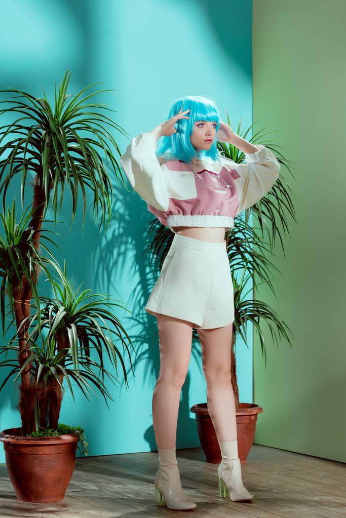 Вид в полный рост стильной девушки в синем парике, притворяющейся долой и отводящей взгляд
 - Фото, изображение