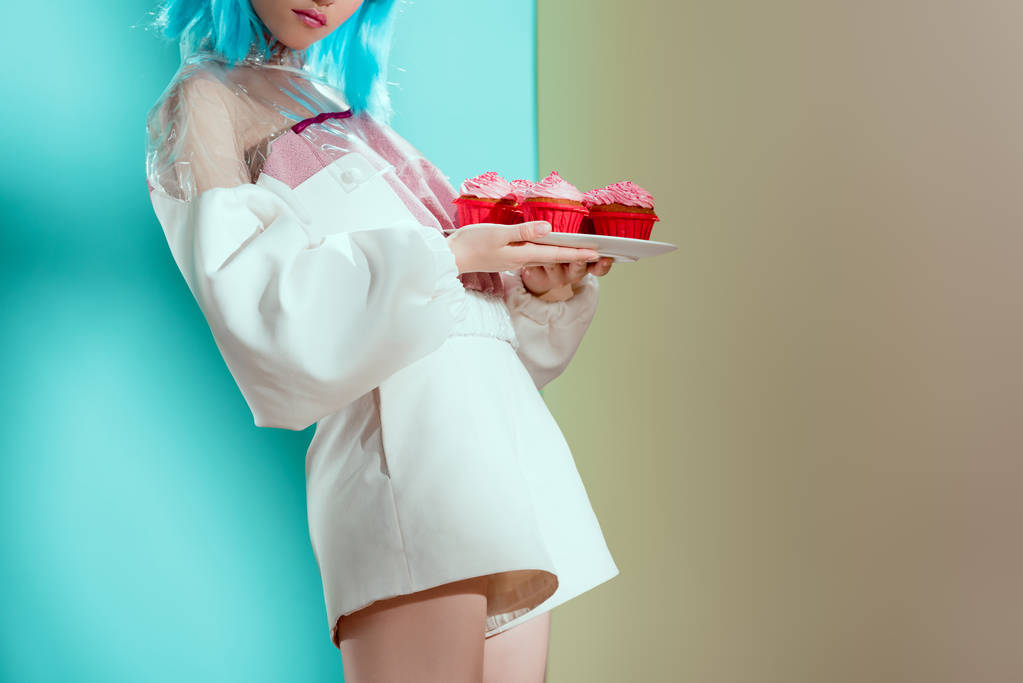 foto recortada de la mujer de moda en peluca azul con deliciosos cupcakes en el estudio
 - Foto, Imagen