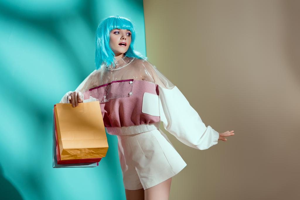 szép elegáns fiatal nő a kék parókát gazdaság bevásárló táskák, és keres el a stúdió  - Fotó, kép