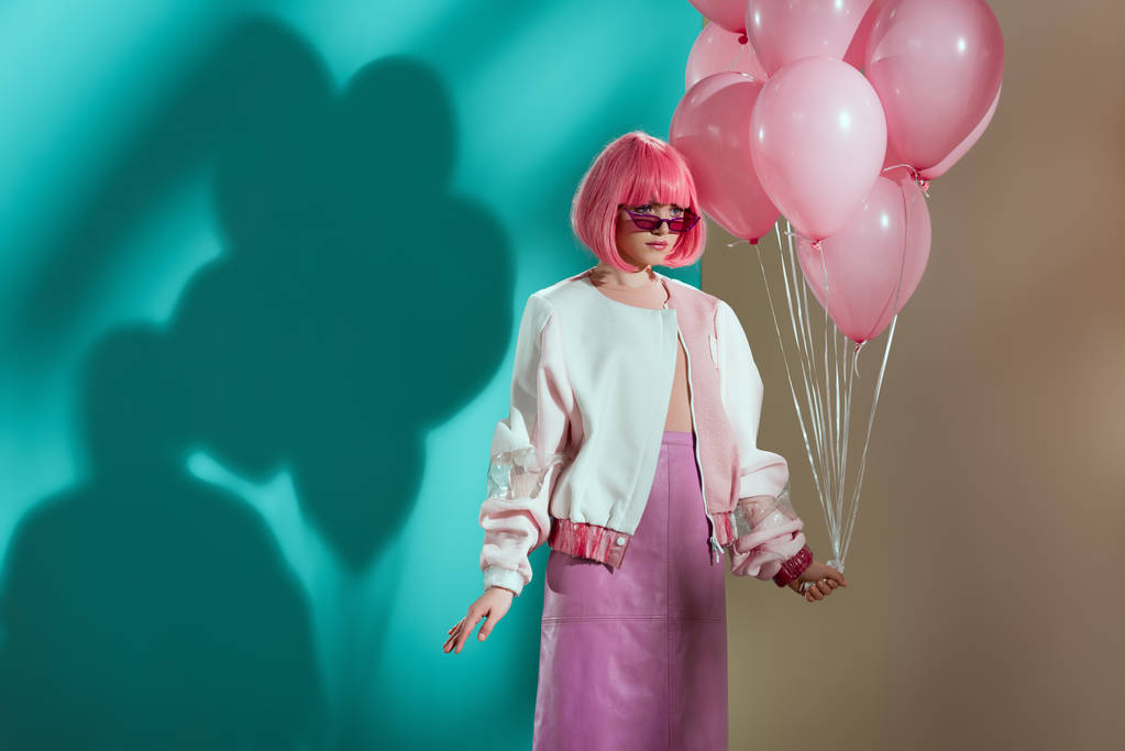 stijlvolle mooi meisje in heldere pruik roze ballonnen te houden en weg op zoek - Foto, afbeelding
