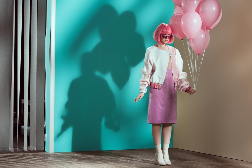 Προβολή πλήρους μήκους κομψό όμορφο κορίτσι σε φωτεινό περούκα κρατώντας ροζ μπαλόνια - Φωτογραφία, εικόνα
