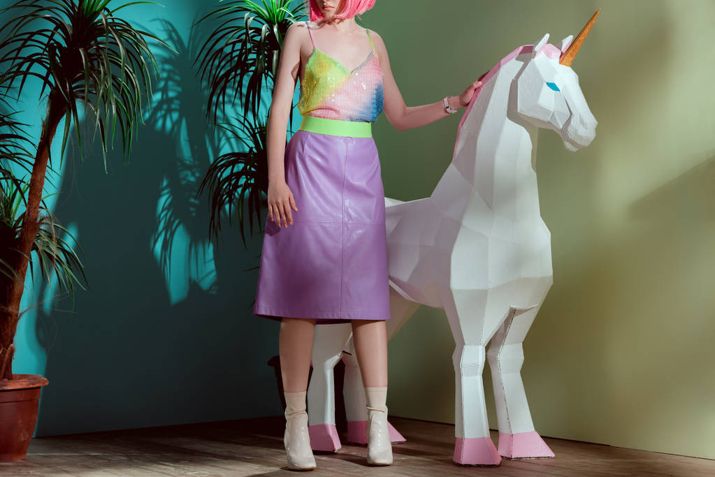 bijgesneden schot van stijlvolle meisje in roze pruik staande in de buurt van de Eenhoorn - Foto, afbeelding
