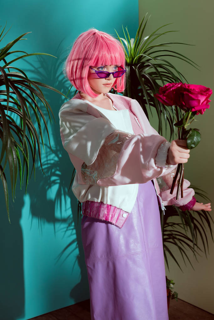 Krásná módní mladá žena v růžové paruka drží růže a hledat dál - Fotografie, Obrázek