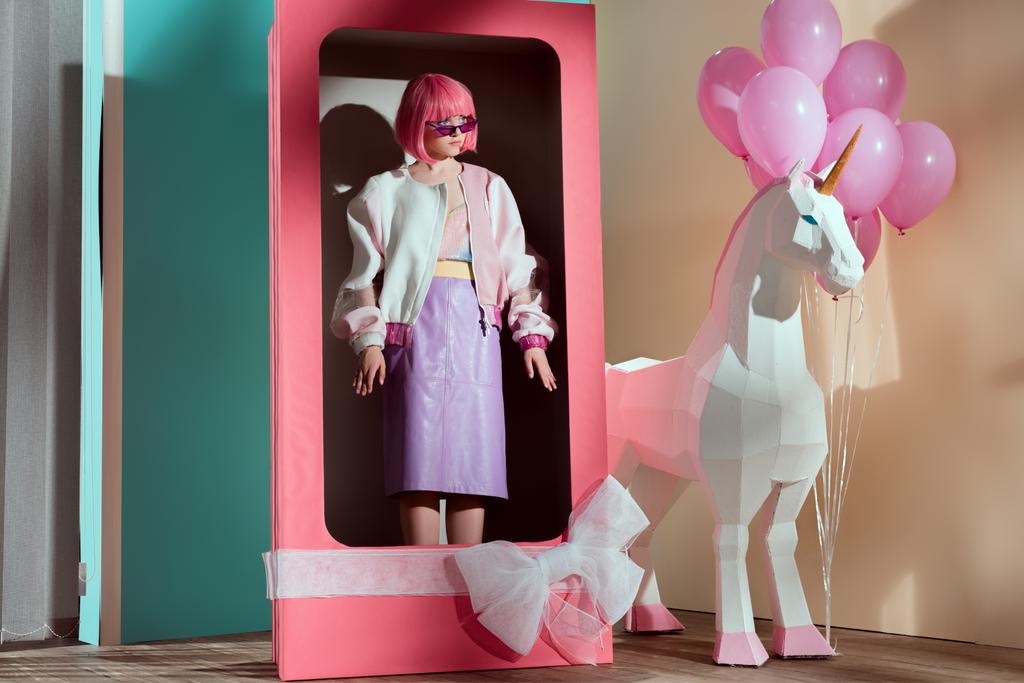 modèle féminin en perruque rose debout dans une boîte décorative avec noeud
 - Photo, image