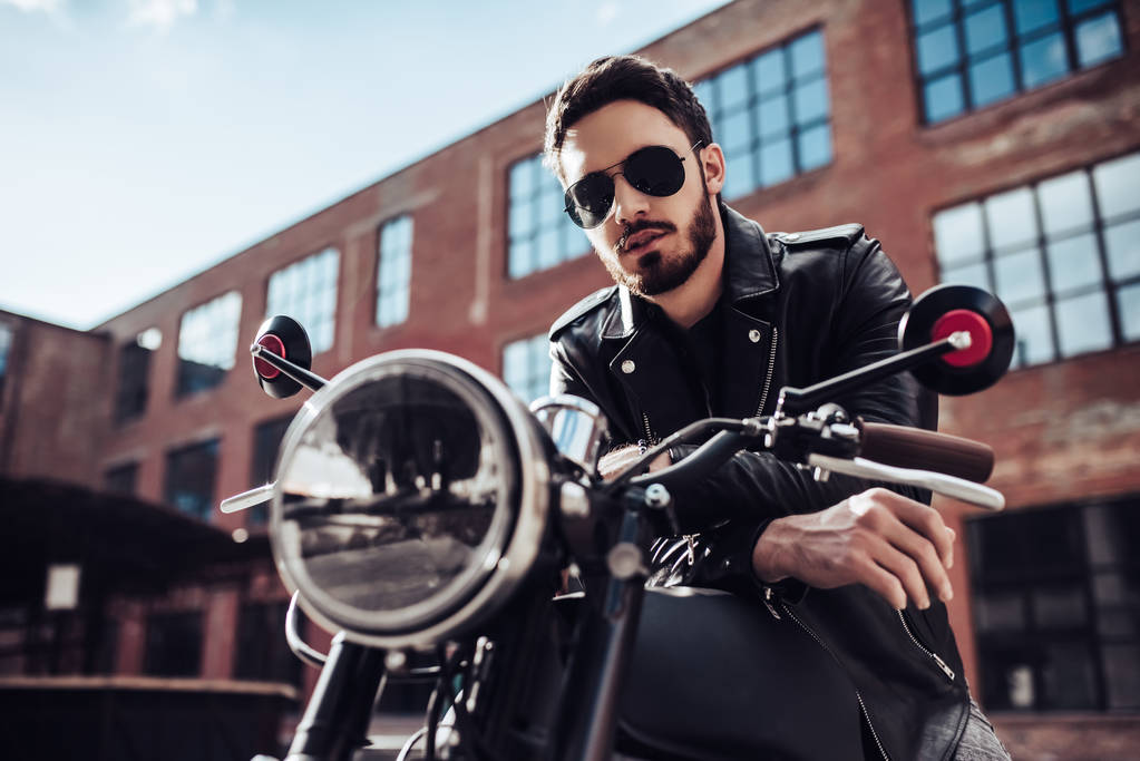 Красивий бородатий байкер з класичним стилем чорний мотоцикл. Кафе гонщик
. - Фото, зображення