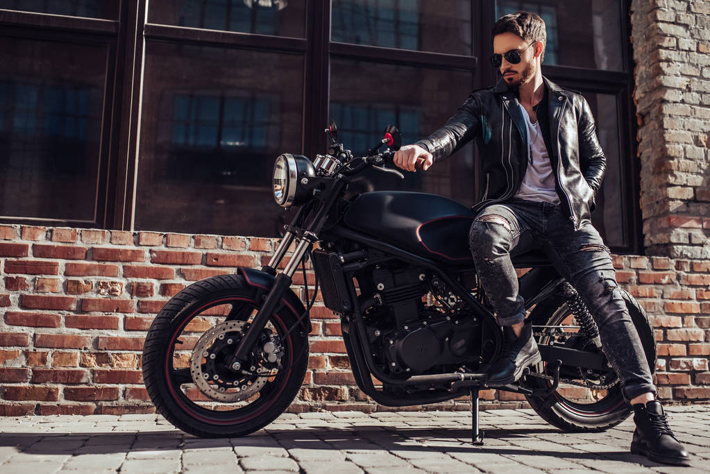 schöner bärtiger Biker mit klassischem schwarzen Motorrad. Cafe Racer. - Foto, Bild