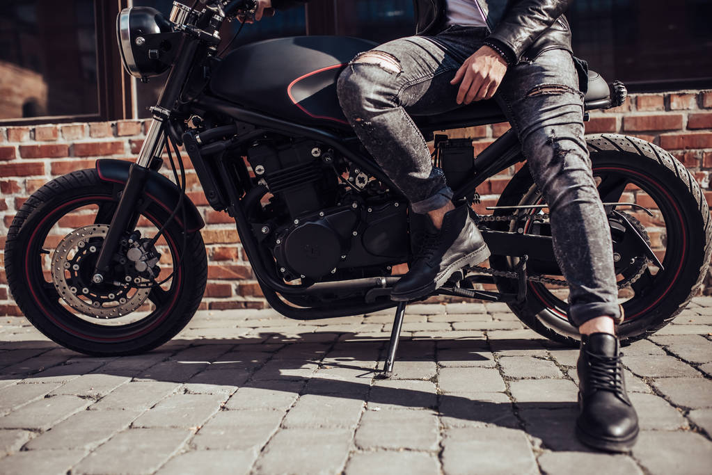 Imagen recortada de motero barbudo guapo con motocicleta de estilo clásico negro. Café corredor
. - Foto, Imagen