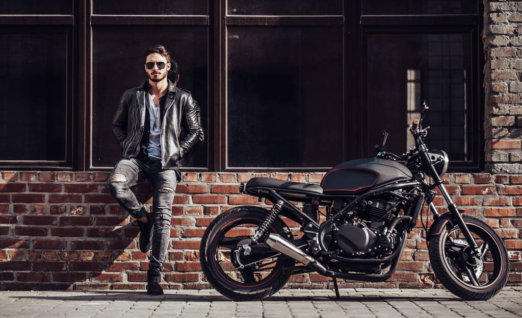 Motociclista barbudo guapo con motocicleta de estilo clásico negro. Café corredor
. - Foto, Imagen