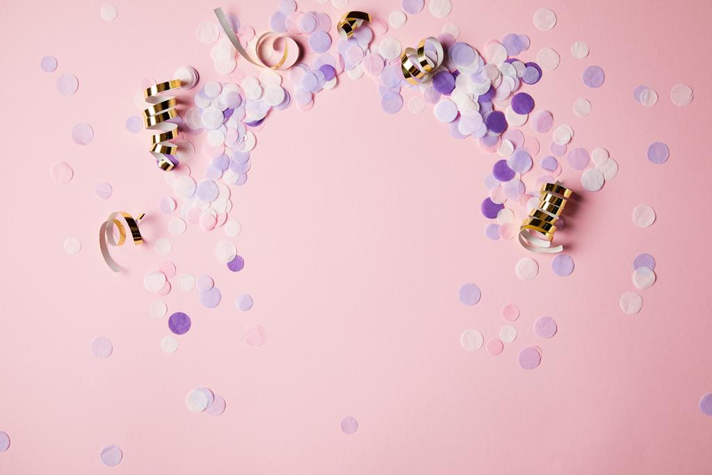 vista elevada de piezas de confeti violeta en la superficie rosa
 - Foto, imagen