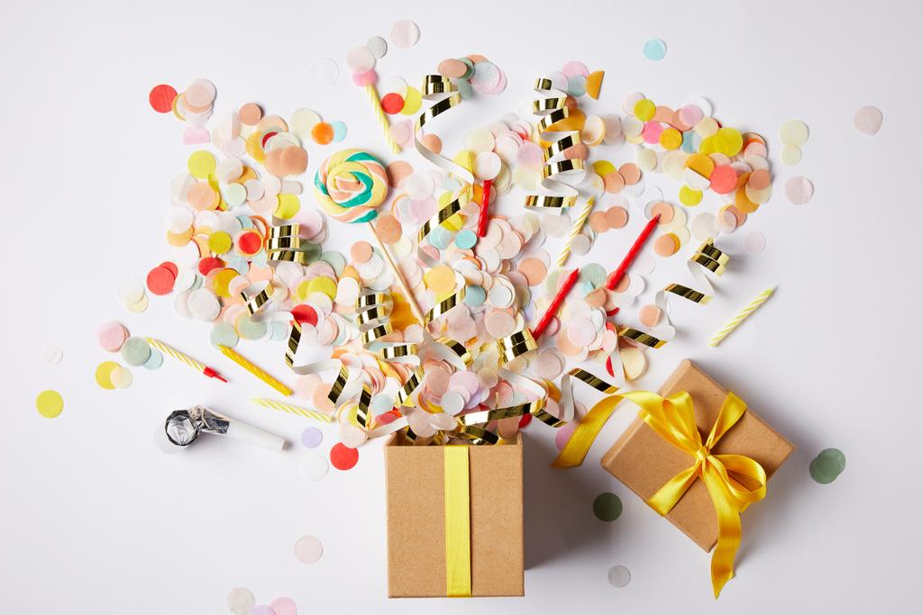 vista superior de la caja de regalo y piezas de confeti dispersas en la superficie blanca
 - Foto, Imagen