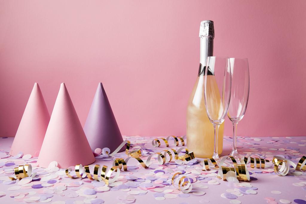 botella de champán, sombreros de fiesta y piezas de confeti en la mesa violeta en la fiesta
 - Foto, imagen