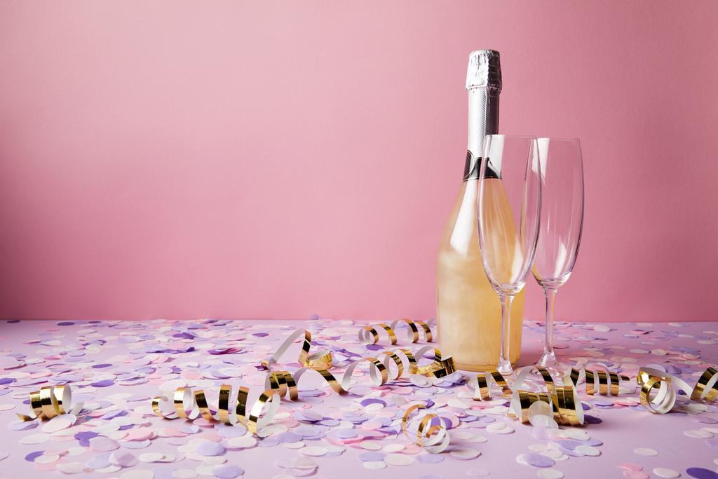 bottle of champagne, glasses and confetti pieces on violet tabletop - Photo, Image