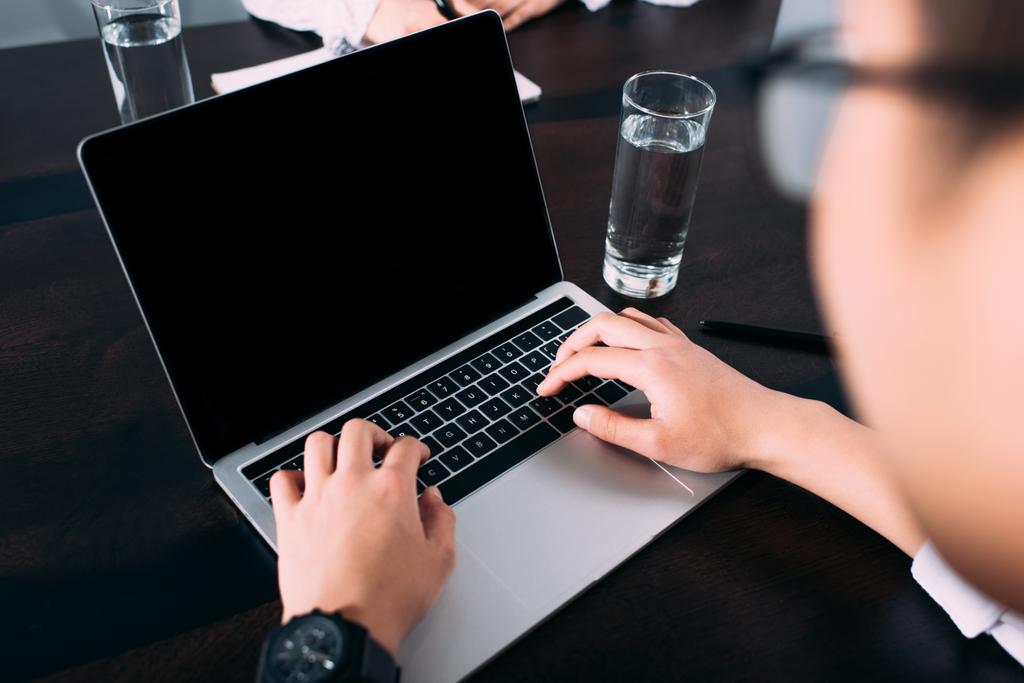 обрізаний знімок бізнесмена, що друкує на ноутбуці з порожнім екраном за столом зі склянкою води
  - Фото, зображення