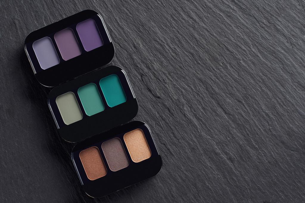 Makeup palettes in a row on dark slate background - Photo, Image