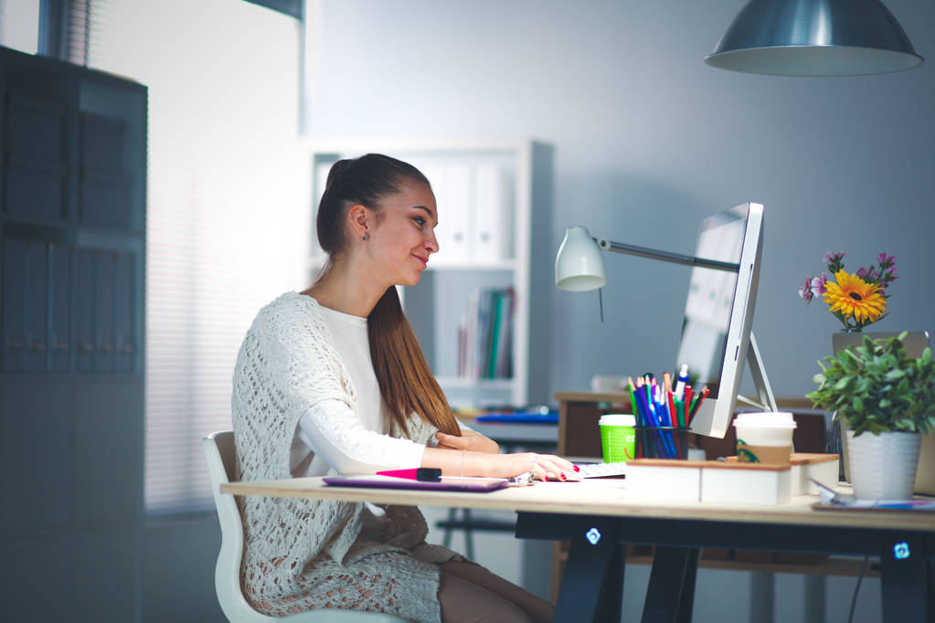 Mujer joven trabajando en la oficina, sentada en el escritorio. Mujer joven
. - Foto, imagen