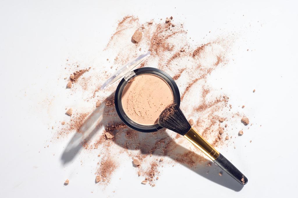 Pressed powder and makeup brush on white background with scattered foundation - Photo, Image