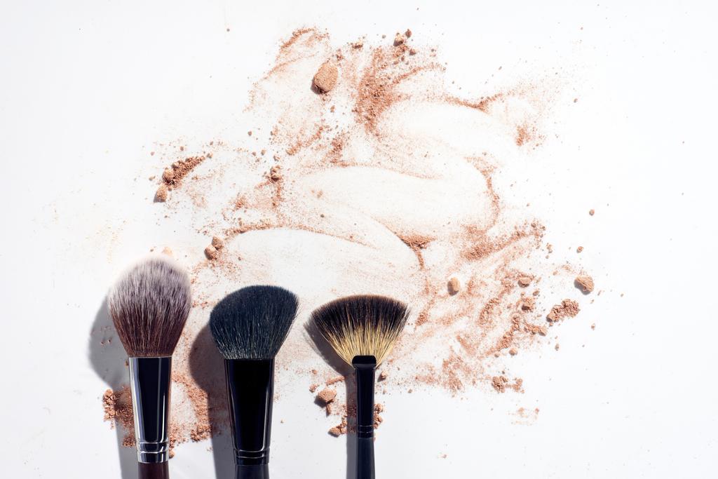Three face brushes on white background with scattered face powder - Photo, Image