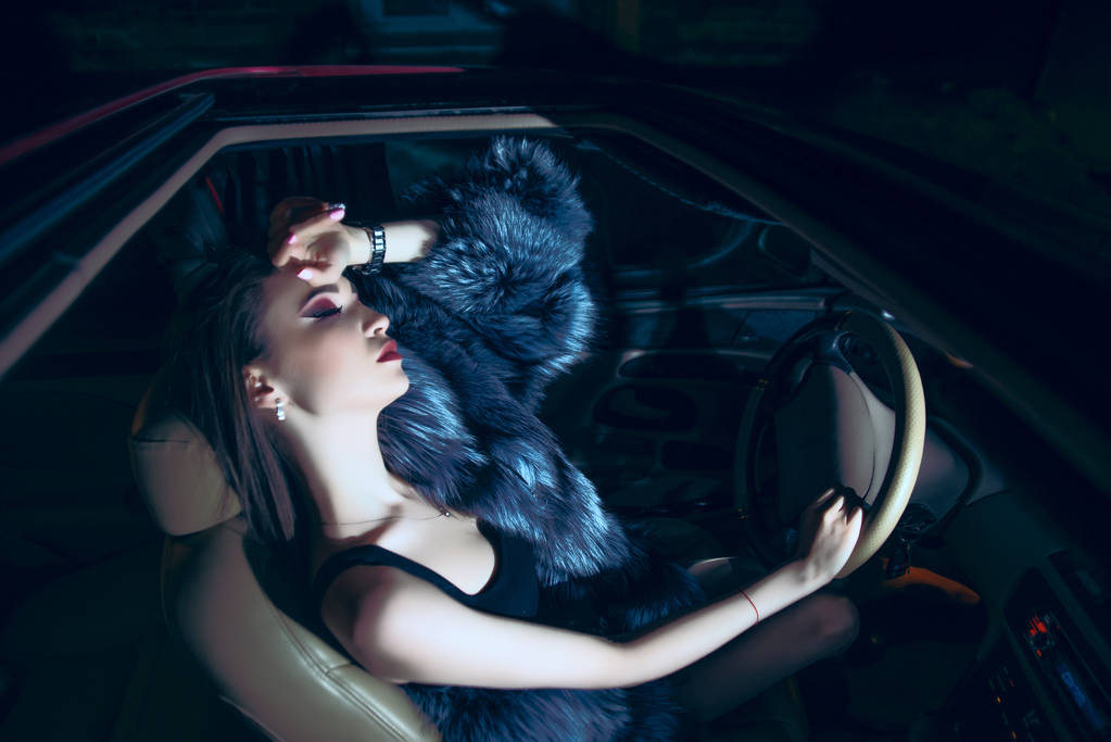Mujer joven sentada con los ojos vestidos en el coche
 - Foto, imagen
