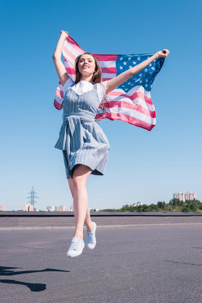 νεαρή γυναίκα άλμα με σημαία των Ηνωμένων Πολιτειών στο τελευταίο όροφο, ημέρα ανεξαρτησίας έννοια  - Φωτογραφία, εικόνα