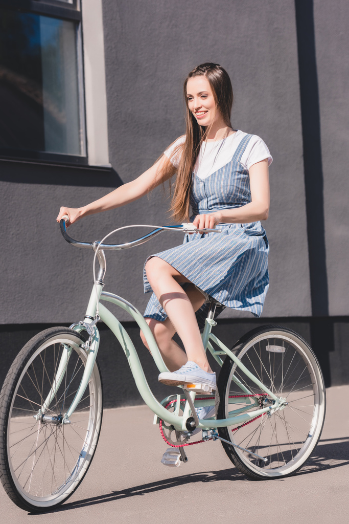 Widok z przodu z młoda kobieta uśmiechający się jazda na rowerze  - Zdjęcie, obraz