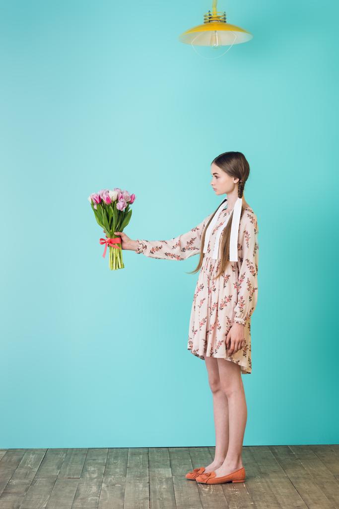 stylisches Mädchen mit Zöpfen im trendigen Sommerkleid mit Blumenstrauß, auf Türkis - Foto, Bild