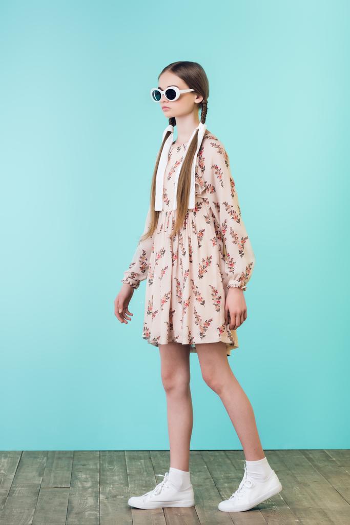 красива дівчина з косами в літній сукні і сонцезахисних окулярах, на бірюзовому
 - Фото, зображення